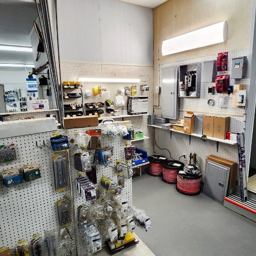 A hardware store aisle featuring pegboard walls with neatly displayed electrical components and tools, creating an organized and practical atmosphere.